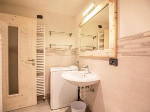ein weißes Badezimmer mit Waschbecken und Spiegel in der Unterkunft Chalet Osmar Appartamento 1 in Campitello di Fassa + 24 Fotos