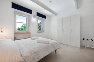 a white bedroom with a large bed and two windows at Casa Mavi in Corte Franca