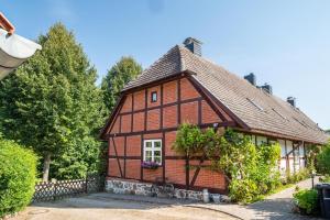 a small wooden house with a fence and trees at Fachwerkferienhaus in Ulrichshusen