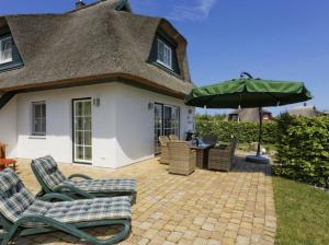 a patio with chairs and an umbrella in front of a house at Villa Sorgenfrei in Zinnowitz