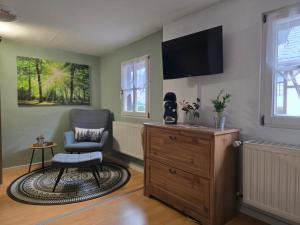 a living room with a chair and a tv on the wall at Huthaus zum Molchner Stollen in Pobershau