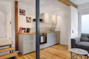 a kitchen with white cabinets and a couch at Kaiserstuhlnest am Rhein in Breisach am Rhein