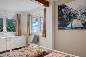 a bedroom with a bed and a dresser and windows at Kaiserstuhlnest am Rhein in Breisach am Rhein
