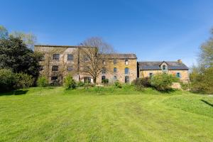 an old brick building with a large field in front of it at L'Erdre au moulin in Joué-sur-Erdre