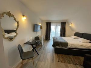 a bedroom with a bed and a mirror and a table at Pensiunea Oficial in Prejmer