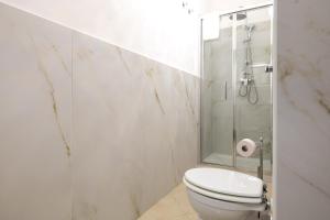 a white bathroom with a toilet and a shower at Appartamento Achates in Acate +12 photos