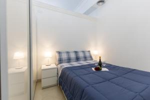 a bedroom with a blue bed with a bottle of wine at Appartamento Achates in Acate