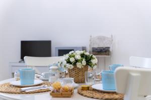 a table with blue dishes and a vase of flowers at Appartamento Achates in Acate