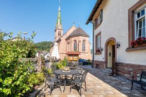 a patio with a table and chairs in front of a church at Landhaus Christophorus in Forbach