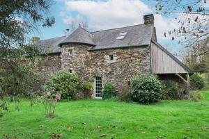 an old stone house in a field of grass at Ker Cado - Chambre d'hôtes in Mauron