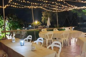 a patio with tables and white chairs and lights at Agriotto Agriturismo in Savona