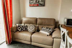 a brown couch with pillows on it in a room at L'éclos des vignes - Appartements haut de gamme avec Spa in Bergheim