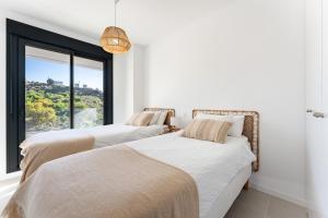 two beds in a room with a window at Middle Views West in Fuengirola +19 photos
