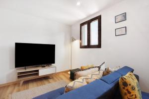 a living room with a blue couch and a flat screen tv at Seaside Haven - Soulful Stays in Porto Moniz