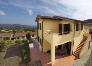 a small yellow house with a dog sitting on a patio at Casa Consuelo App. 2 (trilocale) in Capoliveri