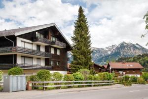 a building with a tree and mountains in the background at Ferienwohnung Bergrose in Obermaiselstein