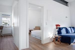 a white bedroom with a blue bed and a mirror at Die Alter Schwede Wohnung 2 in Vechta