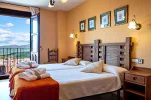 two beds in a room with a large window at Las Puentes 2 in Candelario