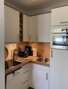 a kitchen with white cabinets and a sink at Ferienwohnungen Felix und Jan in Horumersiel