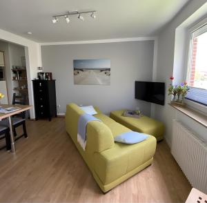 a living room with a yellow couch and a table at Ferienwohnungen Felix und Jan in Horumersiel