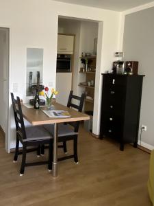 a dining room table with two chairs and a black cabinet at Ferienwohnungen Felix und Jan in Horumersiel