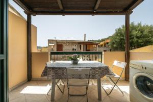 a table and chairs on a balcony with a washing machine at Casa Vacanza Casi 2 in Villasimius