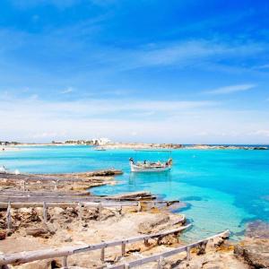 a boat in the water next to a beach at Apartamento Trilo 24 in Es Pujols