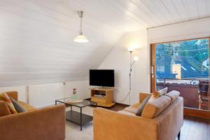 a living room with two couches and a tv at Ferienwohnung Waldblick in Simonswald