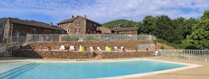 a swimming pool in front of a building with a stone wall at Les Gîtes du Mas Lachamp in Gravières