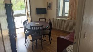 a dining room with a table and chairs and a television at Appartement rochenoir in Saint-Jean-de-Maurienne