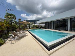 a swimming pool with two chairs and a house at Coconut Villa 8 in Ban Thung