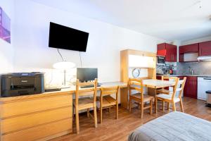a kitchen and dining room with a table with a television at Les cybeles - studio 3 personnes in Brides-les-Bains