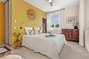 a bedroom with a white bed and a yellow wall at Villa Chantegrive in Roquebrune-sur-Argens +30 photos