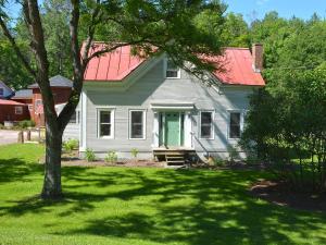 a white house with a red roof and a green door at Hyde Away Inn in Waitsfield