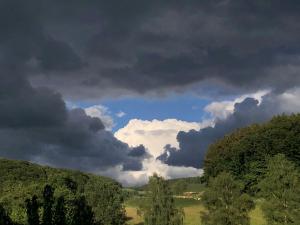 a cloudy sky with trees in a field at Ferienwohnungen Familie Schauerte in Schmallenberg
