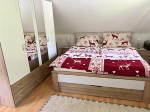 a bedroom with a bed with red comforter and a mirror at Ferienhaus Maierhofer in Fischbach