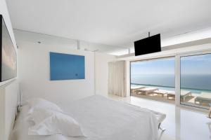 a white bedroom with a bed and a view of the ocean at Casa Nirvana - Penthouse in Sitges +29 photos