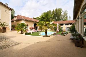 a courtyard with a pool and a palm tree at Chambres d'hôtes Le Pré Fleuri in Saint-Sulpice-de-Roumagnac