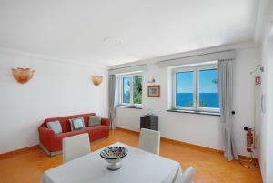 a living room with a table and a red couch at Suite Tramonto in dependance in Conca dei Marini