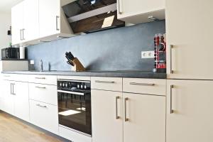 a kitchen with white cabinets and a stove top oven at Hq16 - Modernes Ferienhaus in Neuenburg am Rhein