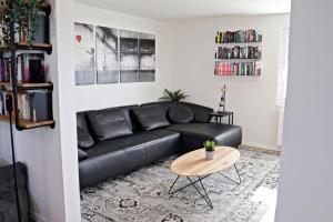 a black leather couch in a living room with a table at Hq16 - Modernes Ferienhaus in Neuenburg am Rhein