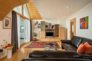 a living room with a black leather couch at Ferienwohnung Haidle in Eriskirch