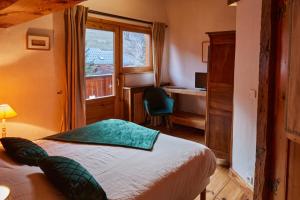 a bedroom with a bed and a window and a desk at Chalet Du Houx in Les Allues