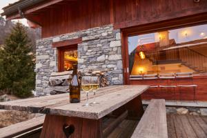 a wooden table with two glasses of wine at Chalet Du Houx in Les Allues