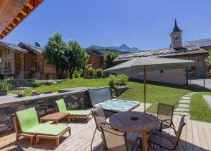 a patio with a table and chairs and an umbrella at Chalet Du Houx in Les Allues