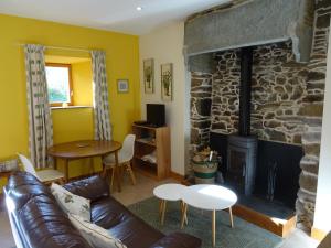a living room with a couch and a stone fireplace at Ensemble De Gites - Pen Ar Voas in Plestin-les-Grèves