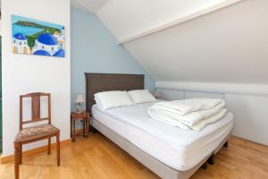a bedroom with a bed with white sheets and a chair at Maison Ker Hélène sur grand jardin in Guérande