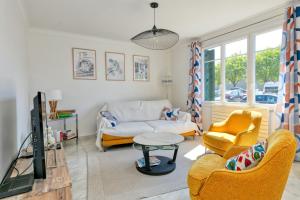 a living room with a couch and a tv at Maison Ker Hélène sur grand jardin in Guérande