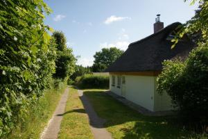 a small white building with a black roof next to a road at Kate unter Reet im Grünen in Buchholz
