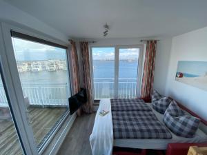 a room with a bed and a balcony with a view at Lootsen Hus by Seeblick Ferien in Olpenitz